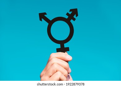 closeup of a young caucasian person holding a transgender symbol against the blue sky