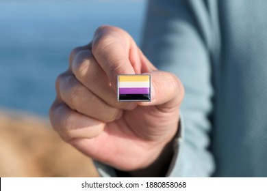 Closeup Of A Young Caucasian Person Showing A Lapel Pin Patterned With A Non-binary Pride Flag