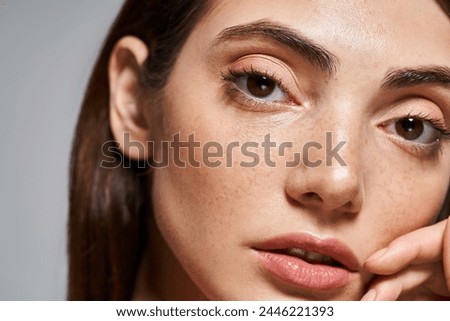A close-up of a young Caucasian woman with mesmerizing brown eyes and clean skin in a studio setting.