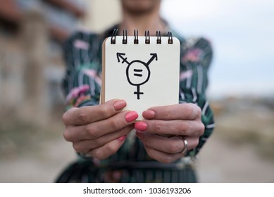 closeup of a young caucasian woman outdoors showing a notepad in front of her with a transgender symbol drawn in it