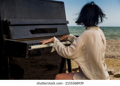 close-up of a young caucassian girl play on old black piano on the sea beach