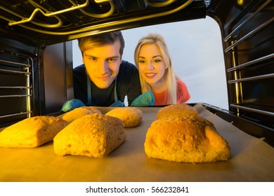 Close-up Of Young Couple Baking Bread In The Oven