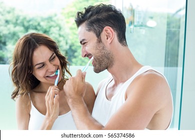 Close-up of young couple brushing teeth in bathroom at home