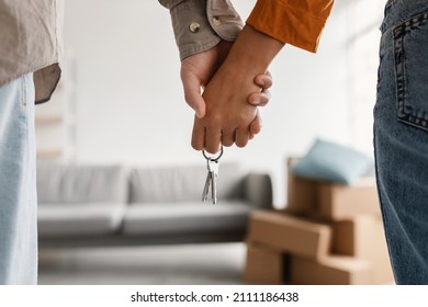 Closeup of young couple holding hands and new house key, moving in together. Unrecognizable boyfriend and girlfriend relocating to their own property, cropped view. Mortgage, real estate concept - Shutterstock ID 2111186438