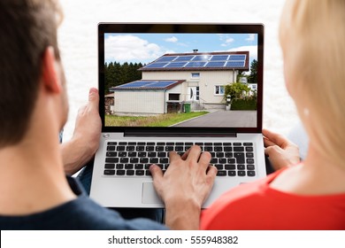 Close-up Of A Young Couple Looking At House On Laptop At Home