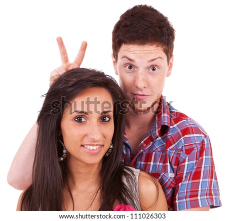 closeup of a young couple - man goofing around behind his girlfriend