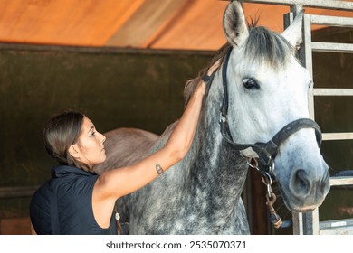 closeup young equestrian gently brushing her horse's mane in the stable after a training session. The rider shows tenderness and care as she tends to her horse, highlighting the bond between them - Powered by Shutterstock