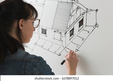 Close-up of a young female architect drawing a sketch for a new famaly home project. Concept of work on technical drawings