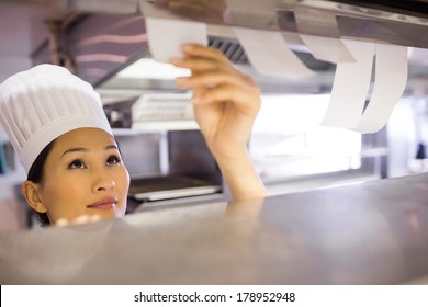 Closeup of a young female chef going through cooking checklist at kitchen counter - Powered by Shutterstock