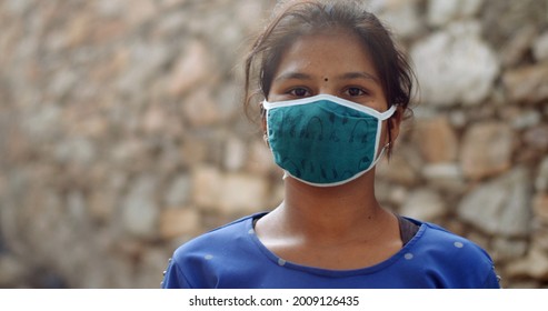 A Closeup Of A Young Female South Asian Child With A Traditional Bindi Wearing A Green Covid Mask