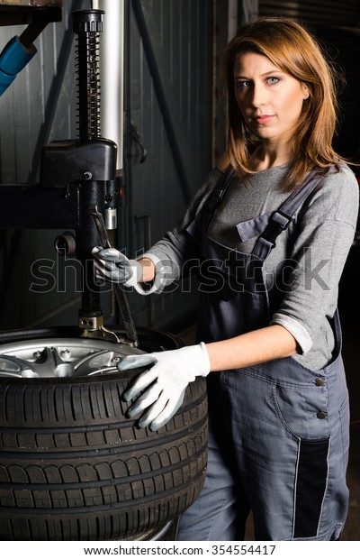 Closeup of a young female
trainee changing  car tyre in a garage - concept for the fact that
more and more women participate in jobs previously typical for men.
