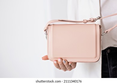 Close-up of a young girl holding a stylish powder-colored bag in her hand. The concept of women's fashion.