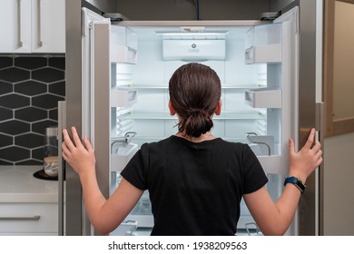 Close-up Of young girl looking into an empty Refrigerator fridge, Looking into empty fridge concept - Shutterstock ID 1938209563