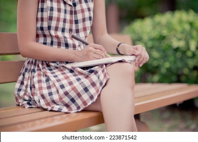 Close-up of a young girl writing into her diary, in the park - Powered by Shutterstock