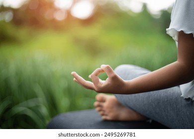 A close-up of a young girl's hands in a meditation pose in the backyard, with sunlight streaming through. - Powered by Shutterstock