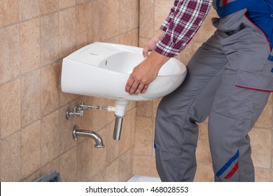 Close-up Of Young Handyman Installing Sink In Bathroom