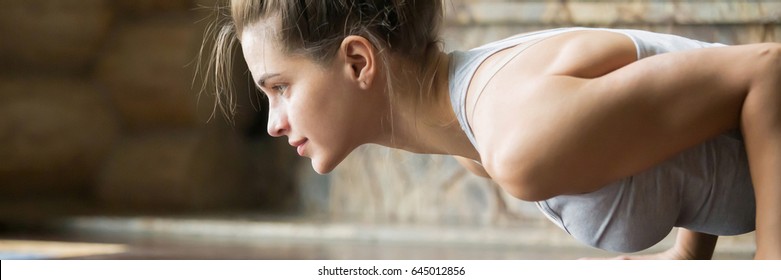 Closeup of young happy attractive woman practicing yoga, doing four limbed staff, push ups or press ups exercise. Horizontal photo banner for website header design with copy space for text 