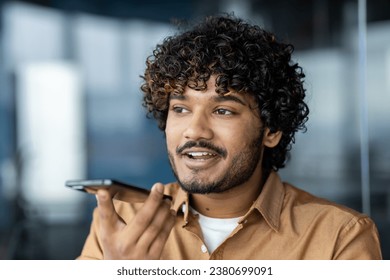 Close-up of a young male businessman using an application on a smartphone to record an audio message, a boss in a shirt, dictating commands, and recording notes on a voice recorder. - Powered by Shutterstock