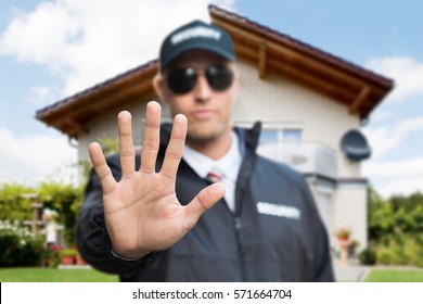 Close-up Of A Young Male Security Guard Making Stop Gesture In Front Of A House