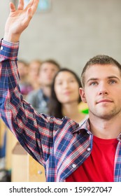 Close-up Of A Young Male Student Raising Hand By Others In A Row At The Classroom