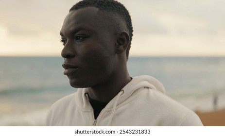 Close-up of young man against the sea stands with his arms crossed on his chest - Powered by Shutterstock