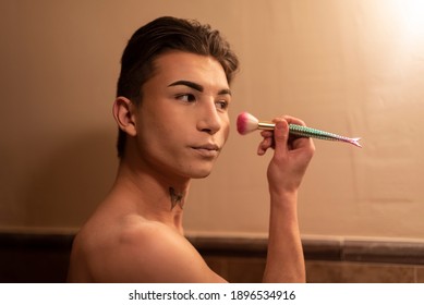 Close-up Of A Young Man Applying Makeup With Brush. Warm Light