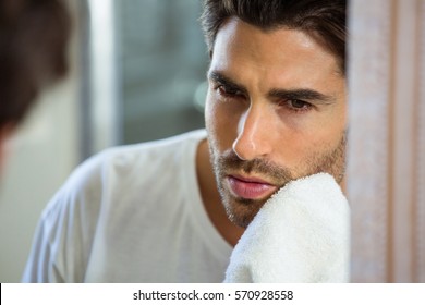 Close-up Of Young Man In Bathroom Wiping His Face With Napkin