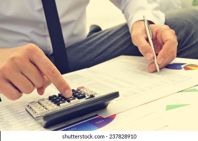 closeup of a young man checking accounts with a calculator