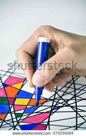 closeup of a young man coloring an abstract drawing, designed by myself, with marker pens of different colors
