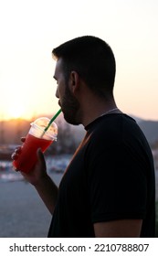 Close-up Of A Young Man Drinking A Slushie Through A Straw At Sunset