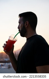 Close-up Of A Young Man Drinking A Slushie Through A Straw At Sunset