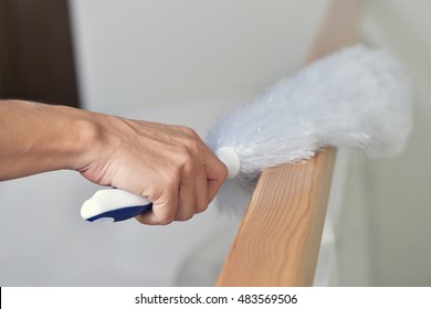 Closeup Of A Young Man Dusting The House With A White Microfiber Duster