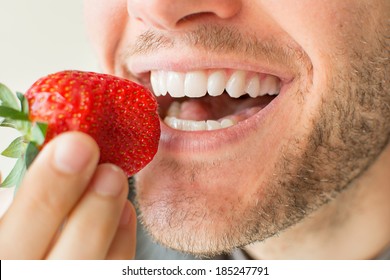 Nahaufnahme eines jungen Mannes, der eine Erdbeere isst