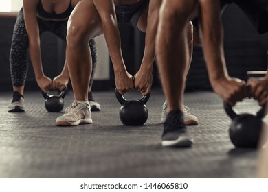 Closeup of young man and fit woman hands lifting kettle bell while squatting at gym. Athlete people doing weight lifting with kettlebell. Group of three young athlete doing crossfit training. - Powered by Shutterstock