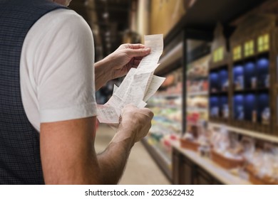 Closeup of young man holding bill to check the price in supermarket