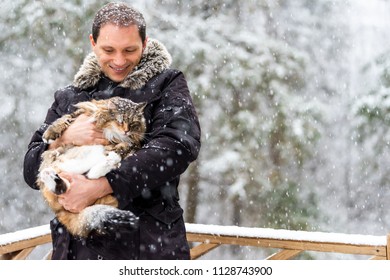 Closeup Of Young Man Holding Maine Coon Cat Outside, Outdoors In Park In Snow, Snowing