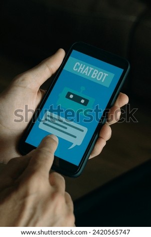 closeup a young man indoors using a simulated chatbot on his smartphone, that reads the text chatbot on its screen
