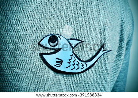 closeup of a young man with a paper fish attached with tape to his back, with a slight vignette added Photo stock © 
