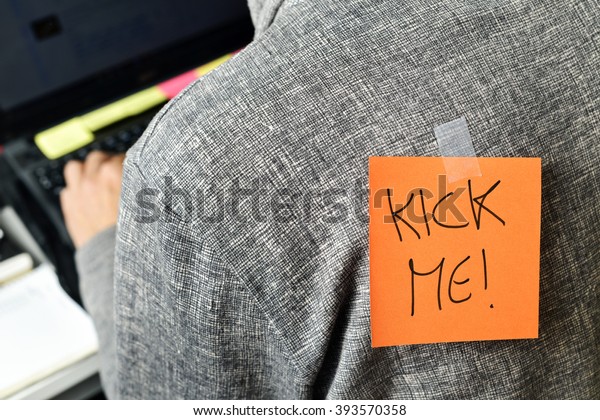 closeup of a young man with a paper with the text\
kick me attached to his\
back