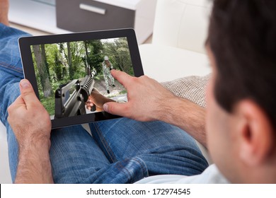 Close-up Of Young Man Playing Game On Digital Tablet At Home