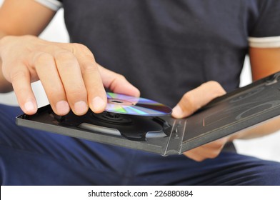 closeup of a young man pulling a DVD or a CD out of its case