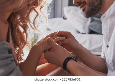 Close-up of young man putting engagement ring on finger of his happy girlfriend - Shutterstock ID 2257856901