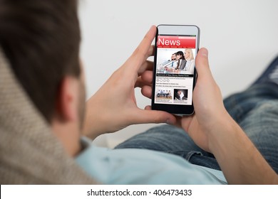 Close-up Of Young Man Reading Online News On Mobile Phone