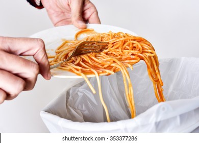 closeup of a young man throwing the leftover of a plate of spaghetti to the trash bin - Powered by Shutterstock