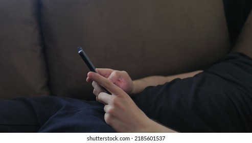 Closeup Young Man Use Smartphone Working From Home Lying On Couch Side View, Wide Photo