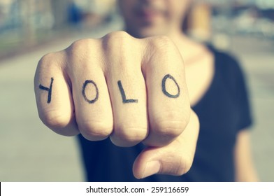 closeup of a young man with the word yolo, for you only live once, tattooed in his hand, with a filter effect - Shutterstock ID 259116659