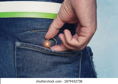 Closeup of a young man's hand put in or taking out a wedding ring in jeans pocket. Concept of infidelity or asking in marriage. Man takes off ring before unfaithfulness. Man makes a marriage proposal.