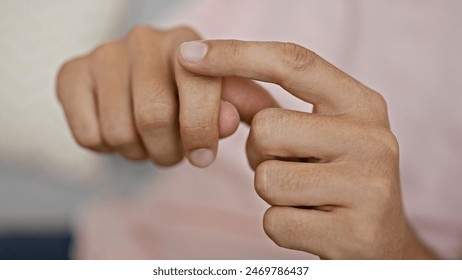 Close-up of a young man's hands using sign language indoor, with a blurred background. - Powered by Shutterstock