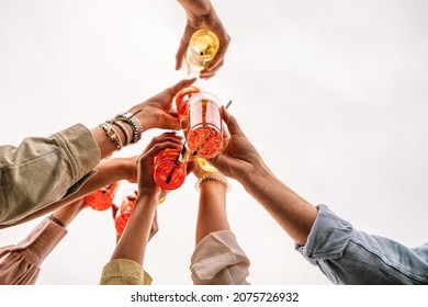 Closeup of young people rising cocktail in plastic for a celebratory toast - people having fun drinking and clinking