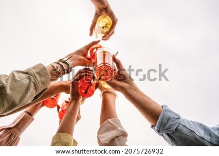 Closeup of young people rising cocktail in plastic for a celebratory toast - people having fun drinking and clinking